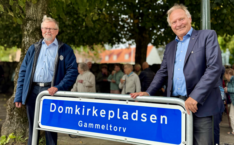 Menighedsrådsformand Ole Rahn og biskop Henrik Stubkjær ved det nye skilt på Domkirkepladsen. 